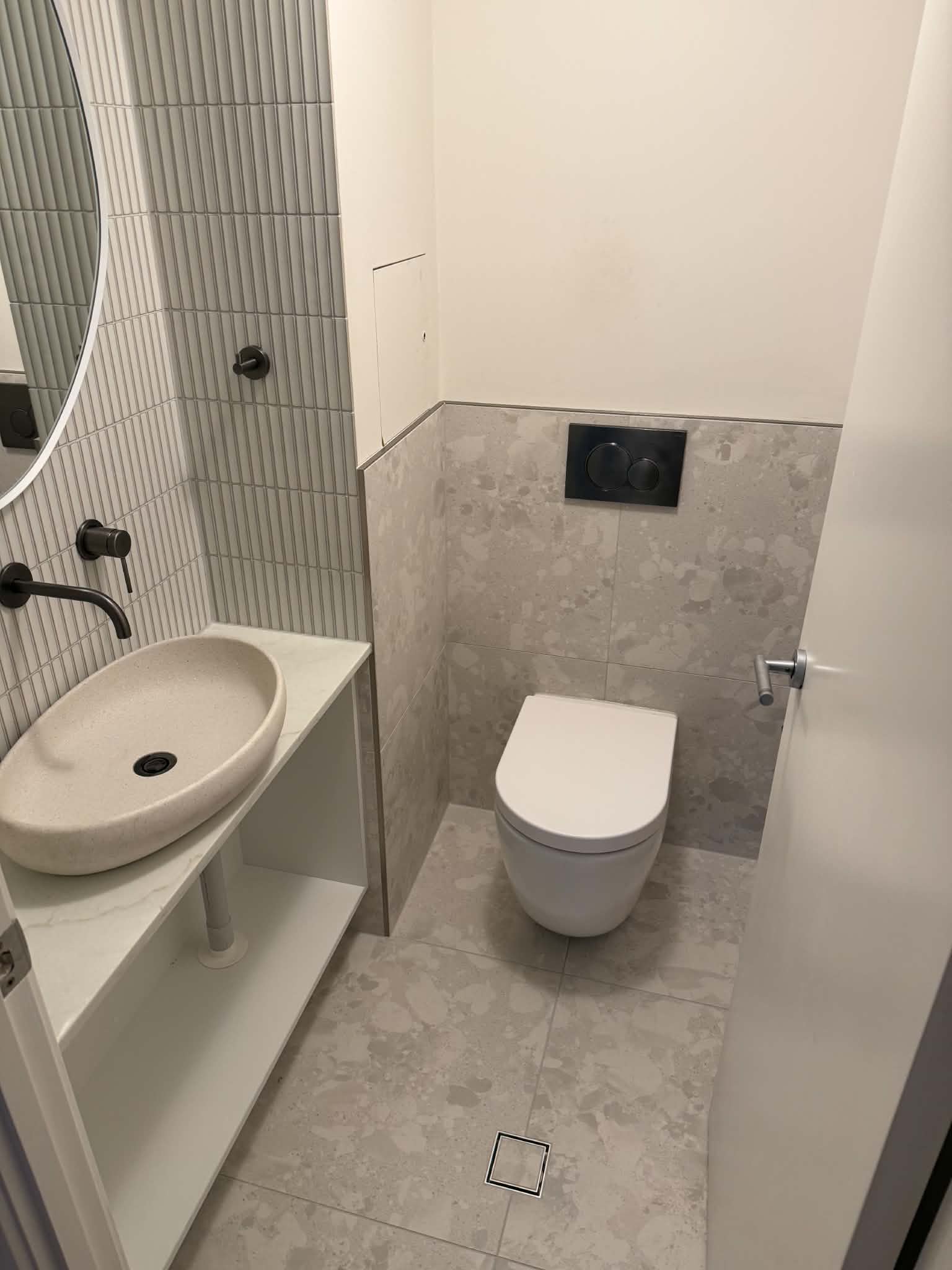 Wall-hung toilet and vanity installation in a tiled bathroom